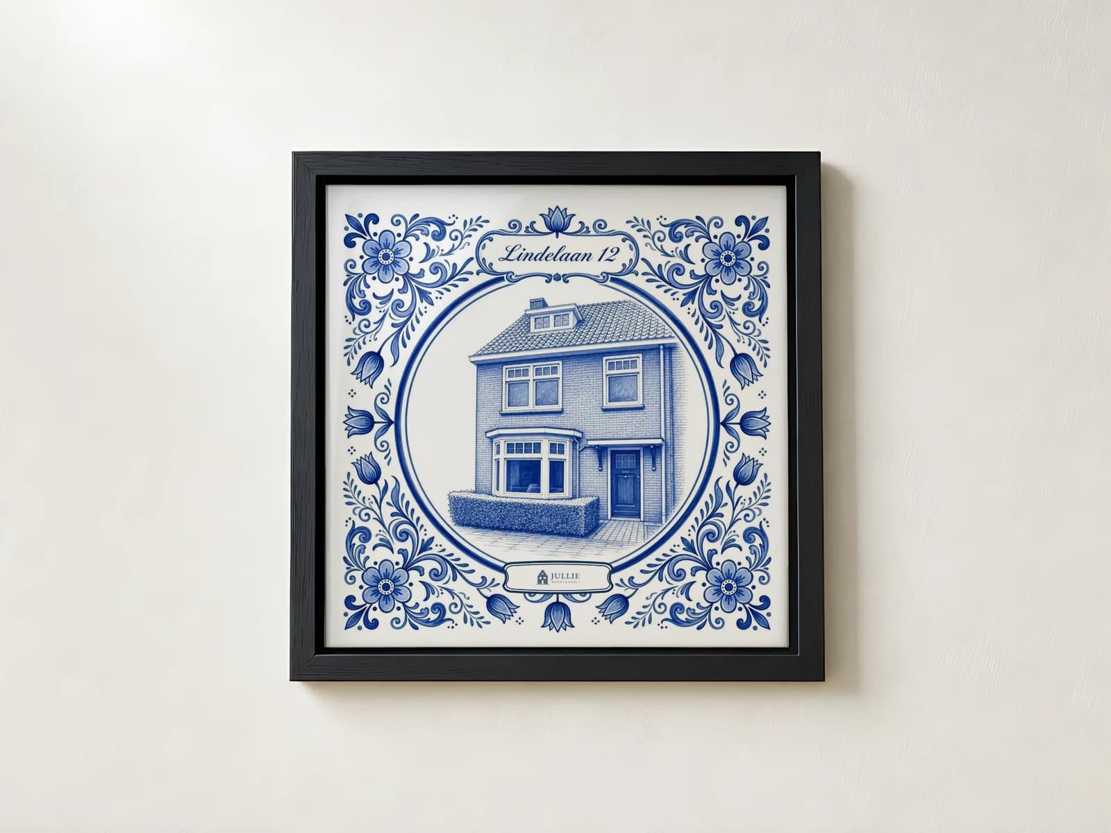 Delfts blauw tegeltje van een woning, verdiept in een zwarte lijst aan de muur